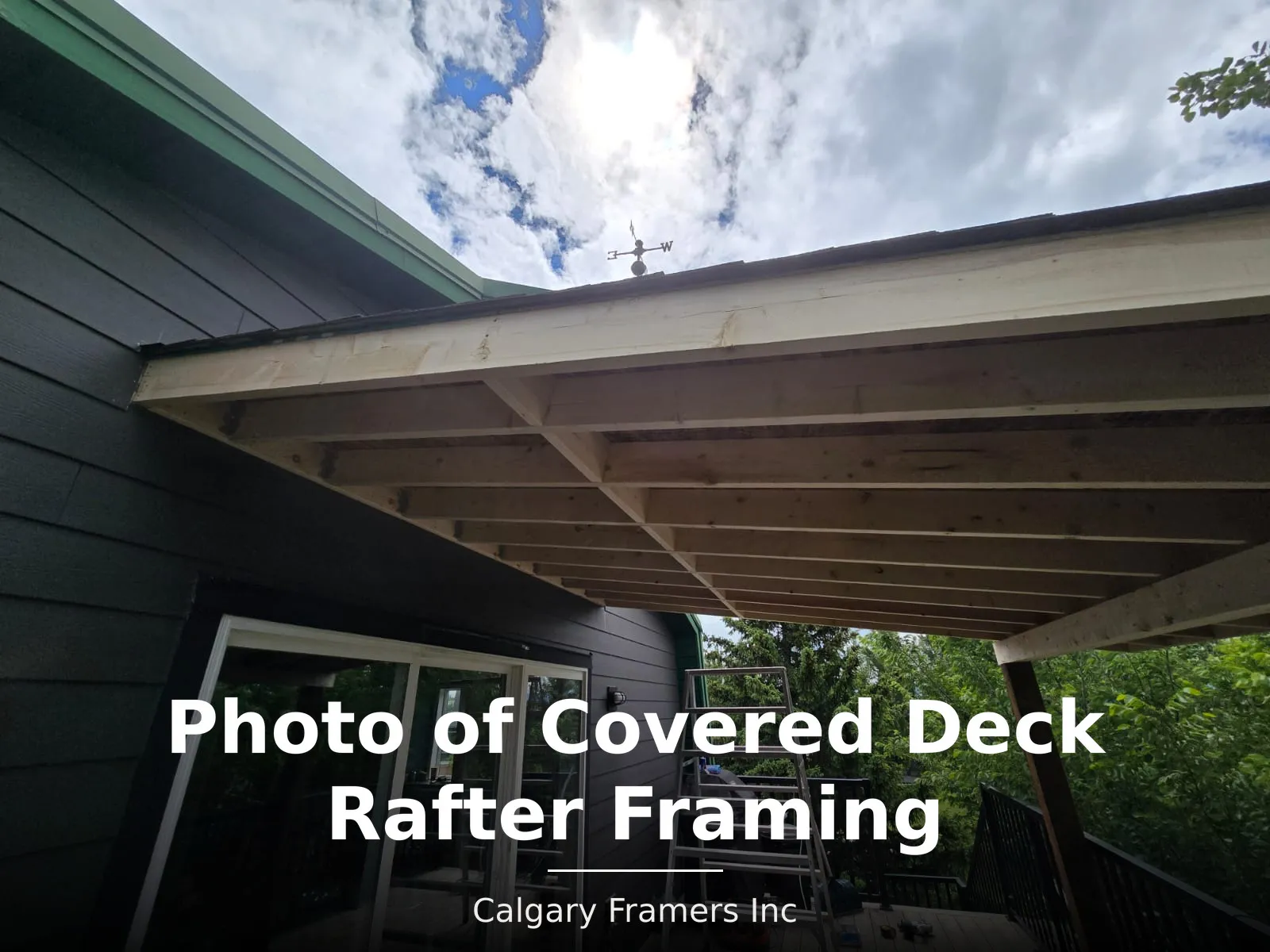 Covered deck rafter framing above a deck with sliding patio doors and Hardie board siding