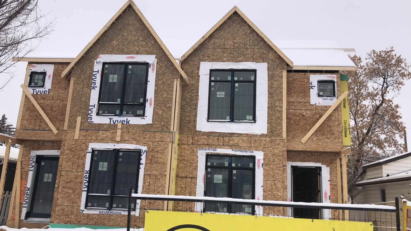 Windows installed into the framed openings of a Calgary duplex, with house wrap lapped around each opening